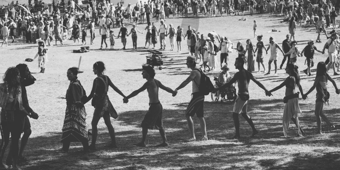 photo en noir et blanc de festivalier.e.s faisant une ronde en se tenant les mains